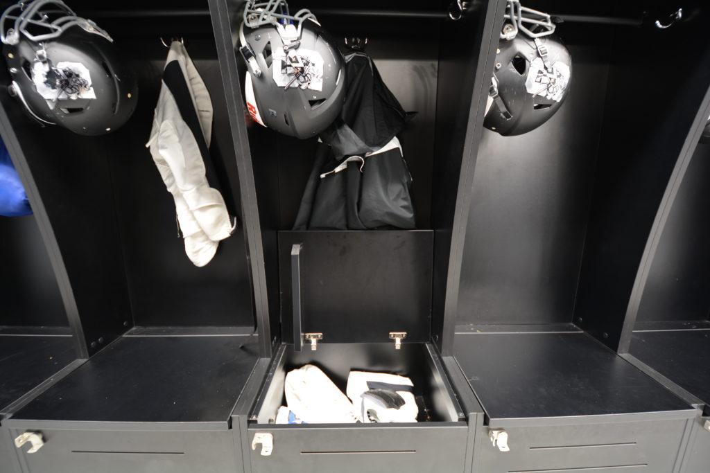 Football helmets hanging inside locker room with extra bench storage black laminate lockers